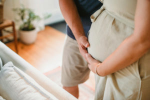 pregnant mom holding belly with father close by