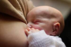 Baby breastfeeding after waking a newborn to feed