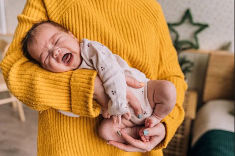 Mother holding a fussy newborn after feeding